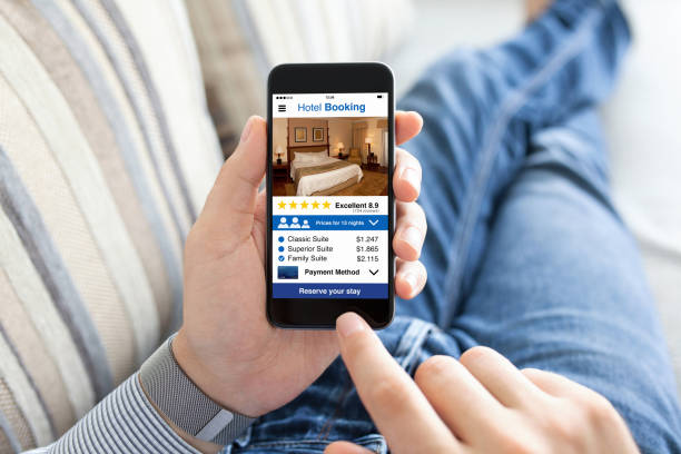 istock man on sofa holding phone with app hotel booking screen 1004121282