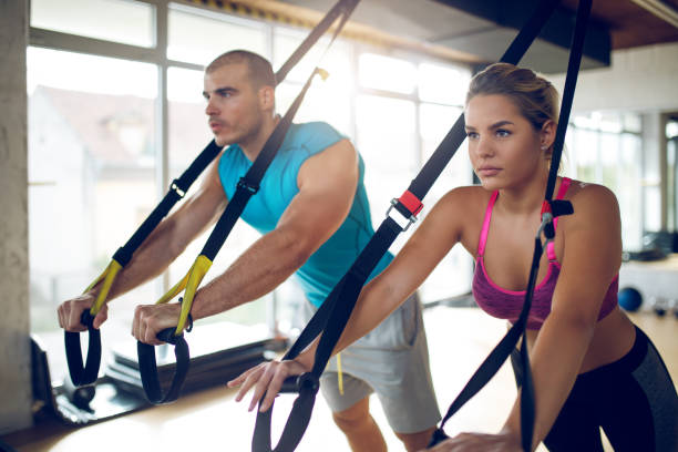 istock Couple doing arm exercises with suspension straps at gym 1004156702
