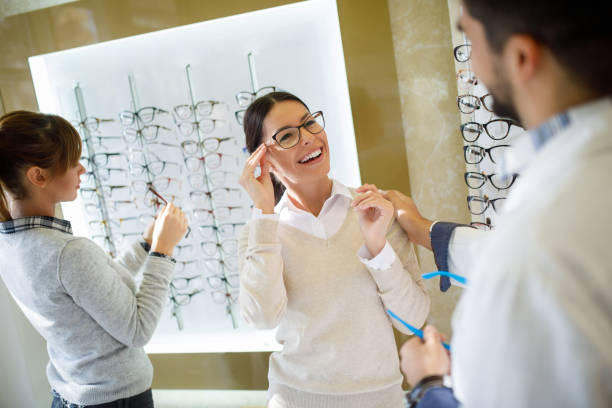 istock Selecting eyeglasses in optical store with assistance of optometrist 1004161868