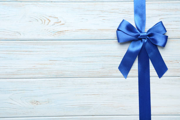 istock Blue bow with ribbon on wooden table 1004164594
