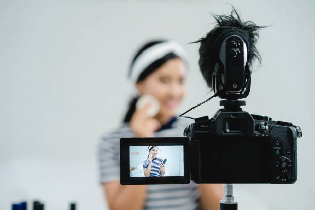 istock Beauty blogger present beauty cosmetics while sitting in front camera for recording video. Beautiful woman use powder while review make up tutorial broadcast live video to social network by internet. 1004165314