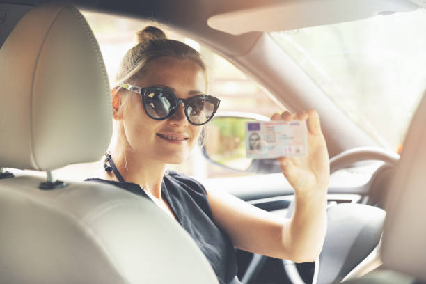 woman showing her new driver license in a car woman showing her new driver license in a car drivers license photos stock pictures, royalty-free photos & images
