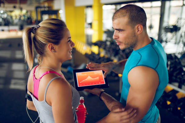 istock Trainer explaining workout regime to young sporty woman 1004183606