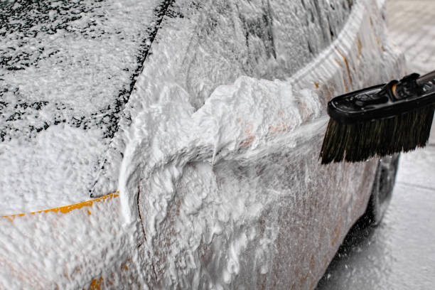 istock Detail on car side mirror completely covered with soap foam, more spraying from brush, when washed in carwash. 1004187006