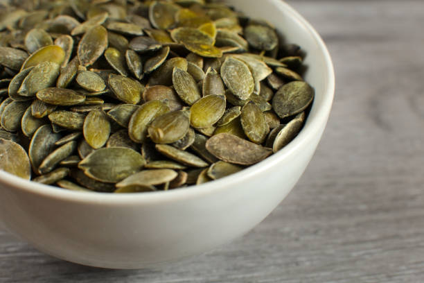 istock Detail on roasted salted pumpkin seeds placed in small ceramic bowl. 1004188032
