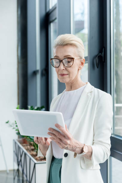 istock attractive senior businesswoman in eyeglasses using digital tablet 1004190460