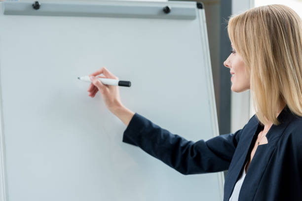 istock smiling professional businesswoman writing on blank whiteboard 1004194356