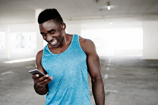 Shot of a sporty young man using a mobile phone while working out in an underground parking lot