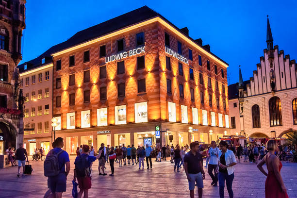 persone in marienplatz all'ora dell'avvento con il grande magazzino illuminato ludwig beck e il vecchio municipio di notte a monaco di baviera, in germania. - editorial concepts and ideas retail place store foto e immagini stock