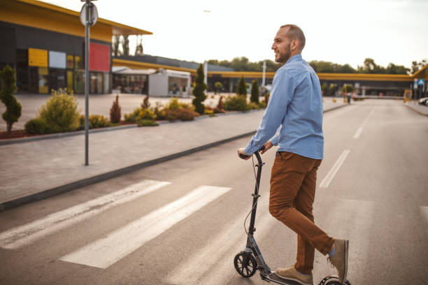 istock Young man riding on push scooter in city 1004195552