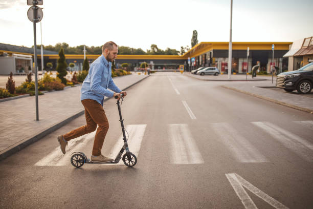 istock Young man riding on push scooter in city 1004195590