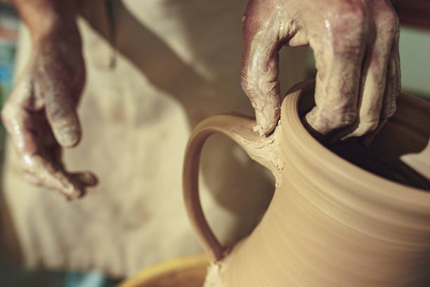 istock Creating a jar or vase of white clay close-up. Master crock. Man hands making clay jug macro 1004198496