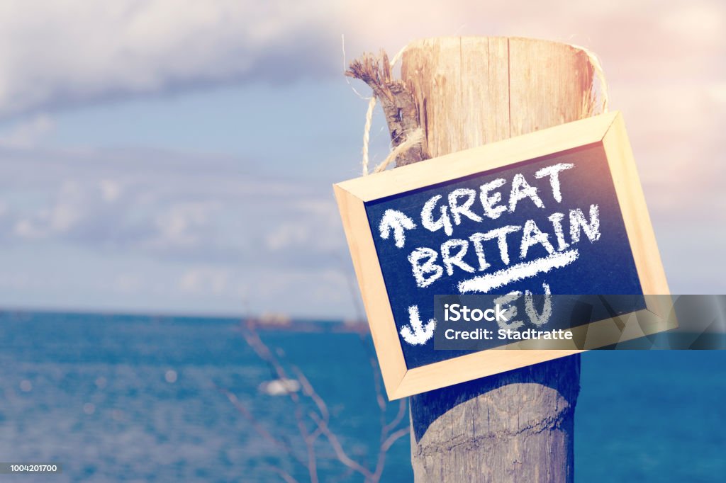 Sea, beach and a sign with arrows to Britain and the European Union EU Sea, beach and a sign with directional arrows to Great Britain and European Union EU Brexit Stock Photo