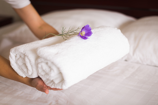 house keeper places towels on a clean white bed for room service.