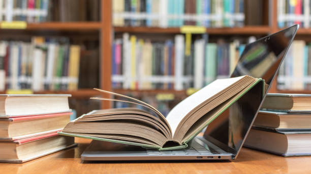 E-learning class and e-book digital technology in education concept with pc computer notebook open in blur school library or classroom background among old stacks of book, textbook archive collection E-learning class and e-book digital technology in education concept with pc computer notebook open in blur school library or classroom background among old stacks of book, textbook archive collection libraries stock pictures, royalty-free photos & images