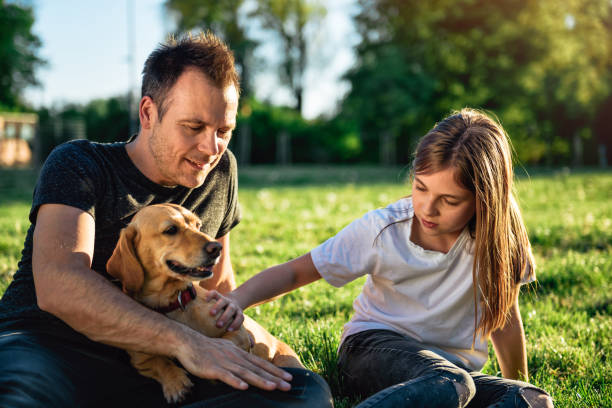 istock Father and daughter relaxing at park with dog 1004221102