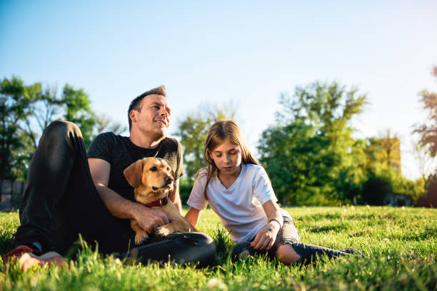 istock Father and daughter relaxing at park with dog 1004222620