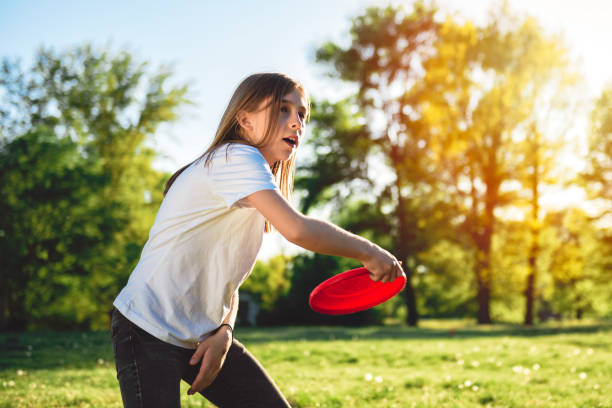 Girl throwing flying disk Girl throwing red flying disk at park plastic disc stock pictures, royalty-free photos & images
