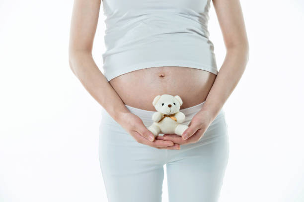 istock Pregnant woman holding a small teddy bear 1004225372