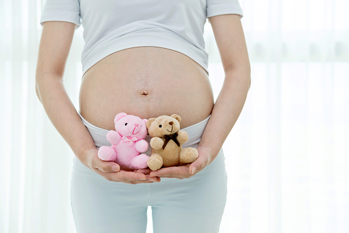 Pregnant woman holding two small teddy bears