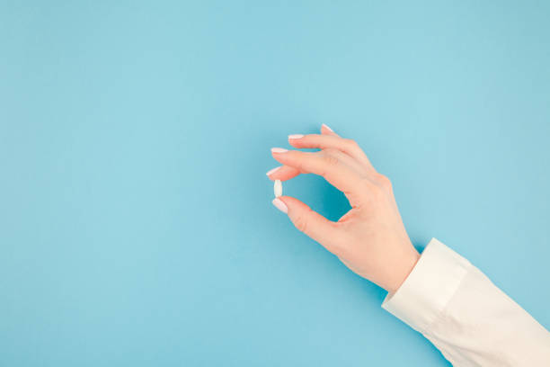 Female hand holding a white pill stock photo