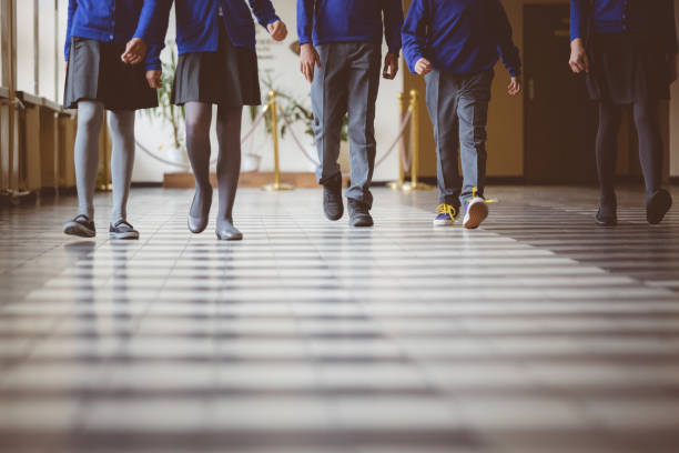 grupo de estudiantes caminando por el pasillo de la escuela - uniforme fotografías e imágenes de stock