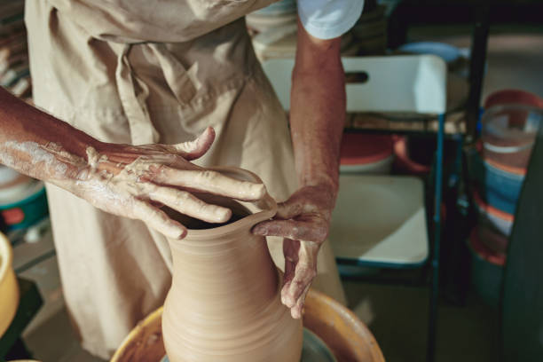 istock Creating a jar or vase of white clay close-up. Master crock. Man hands making clay jug macro 1004240652