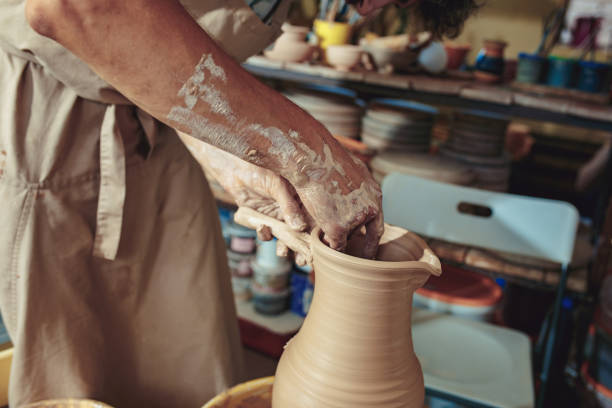 istock Creating a jar or vase of white clay close-up. Master crock. Man hands making clay jug macro 1004242992