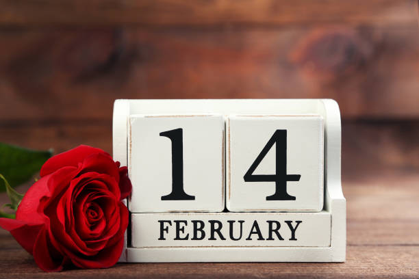 istock Red rose with white cube calendar on brown wooden table 1004247938