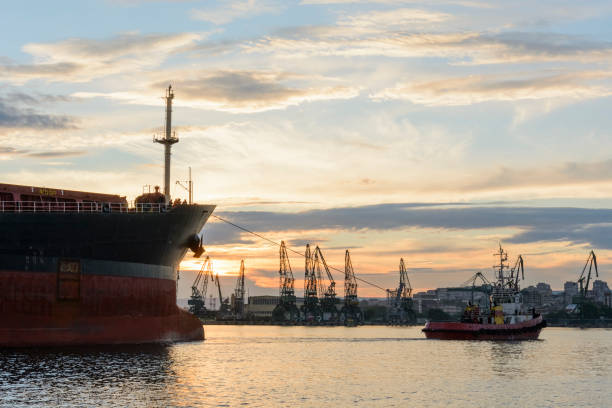 istock Tug boat entering the harbor with big cargo boat. 1004248254