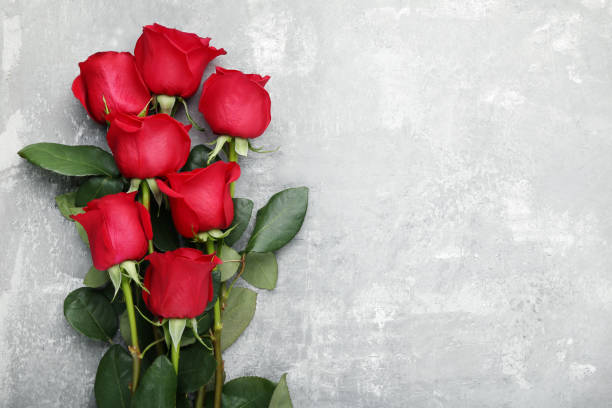 istock Bouquet of red roses on grey wooden table 1004249104