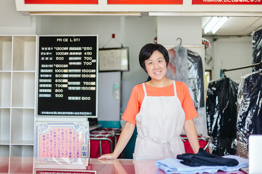 A portrait of a happy female dry cleaning shop owner.