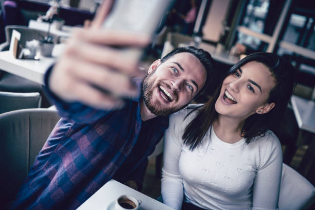 istock Cute Couple Taking Selfie While Drinking Coffee In Restaurant 1004251504
