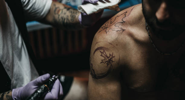 istock Tattoo master making tattoo on customer's shoulder 1004253724