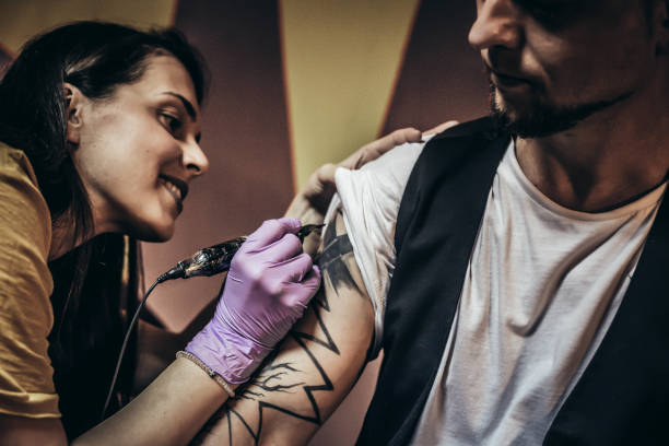istock Artist making tattoo on male customer's hand 1004253968