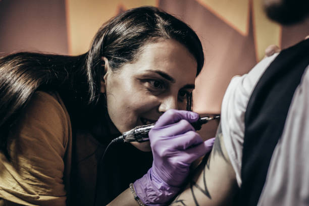 istock Artist making tattoo on male customer's hand 1004254068