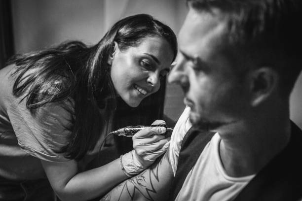 istock Artist making tattoo on male customer's hand 1004254080