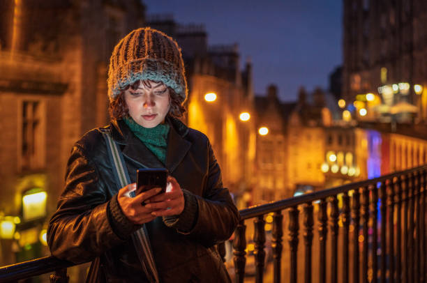 Writing a smart phone message alone in the city at dusk