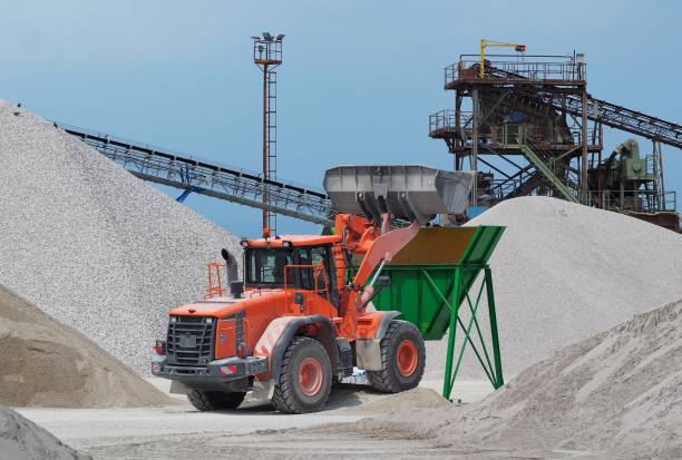 istock Red bulldozer at work on a green hopper under the conveyor belts in a gravel pit 1004263664