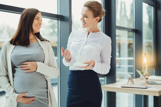 Curious boss asking questions while talking to a pregnant employee