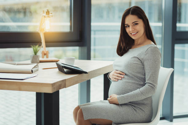 enceinte comptable jeune touchant son ventre et l’air heureux - anticipation smiling touching image technique photos et images de collection