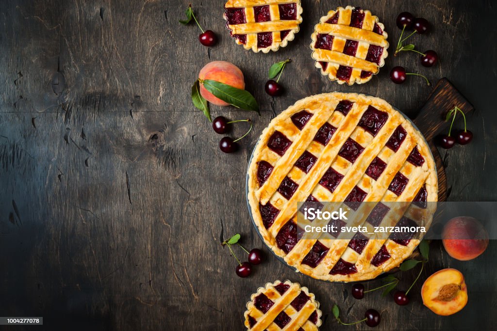 Homemade cherry pie on rustic wooden background Homemade cherry pie on rustic background with cherries and peaches Sweet Pie Stock Photo