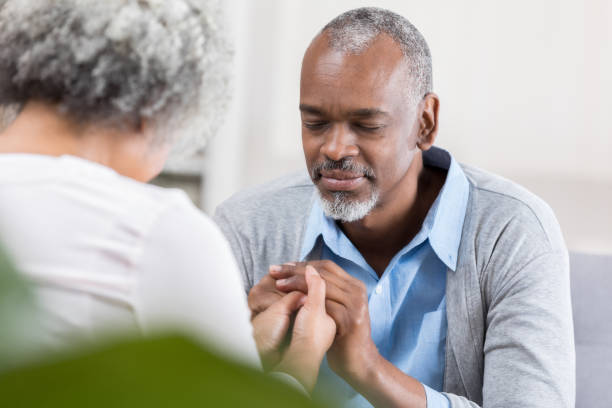 istock Senior man prays with wife at home 1004303814