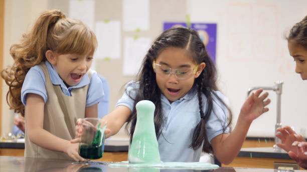 istock Little girls jump back as a flask overflows in science class 1004306498