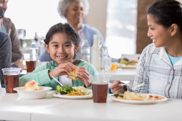istock Little girl enjoys a meal at a soup kitchen 1004308608
