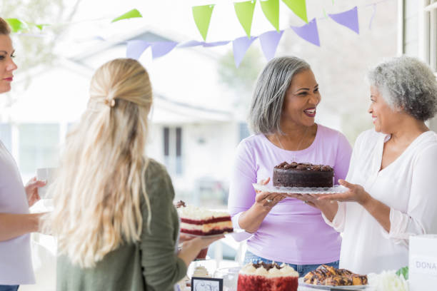 istock Female friends sell cakes during bake sale 1004309178