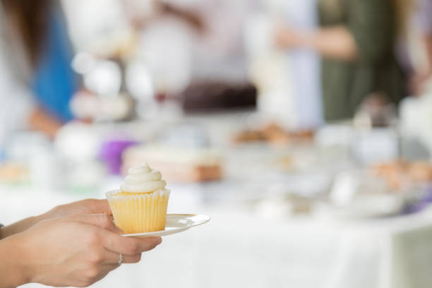 istock Unrecognizable woman hold vanilla cupcake at bake sale 1004309246