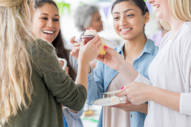 istock Young friends 'toast' cupcake at bake sale 1004309266