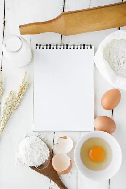 milk, eggs, flour and kitchen tools on white table