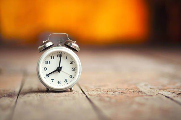 istock Retro alarm clock on a wooden table background 1004349562